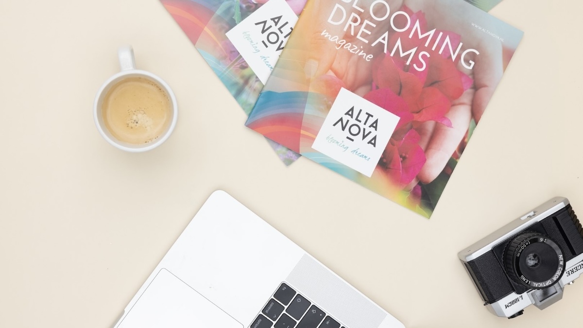 Sfeerbeeld van drukwerk met koffie, camera en laptop in beeld