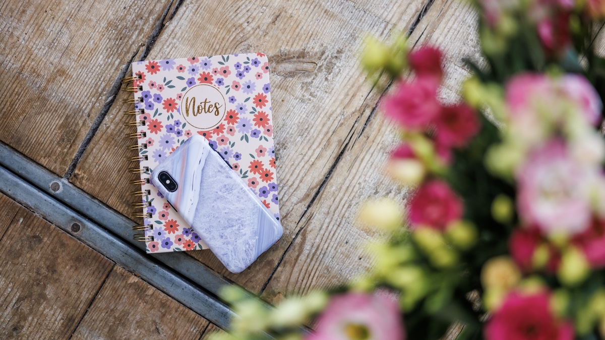 Sfeerbeeld met telefoon, notitieboekje en bloemen